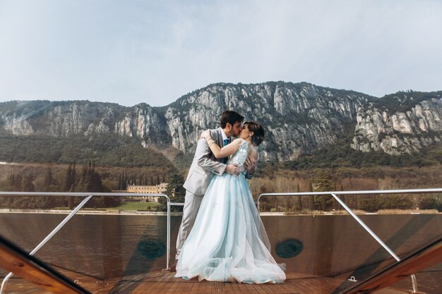 El novio besa a la oferta tímida de la novia en el barco sobre el lago