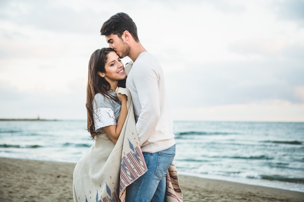 Novio besando a su novia en la frente en una playa
