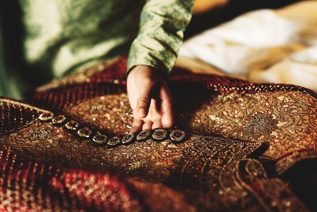 El novio en camisa verde toca su sherwani rojo