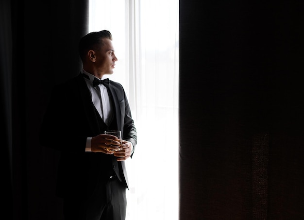 Foto gratuita novio confiado con un vaso de bebida para la ceremonia