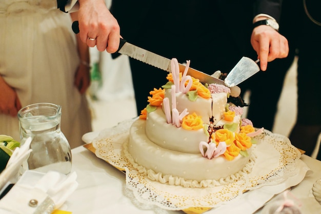 Foto gratuita el novio corta un sabroso pastel de bodas