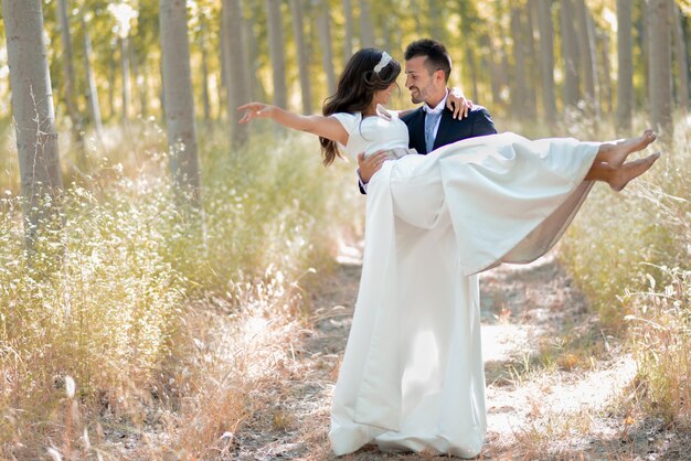 Novio feliz sosteniedo a la novia en el campo