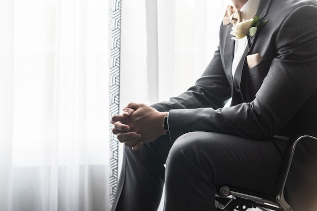 Novio guapo en un traje negro rezando antes de la ceremonia de la boda