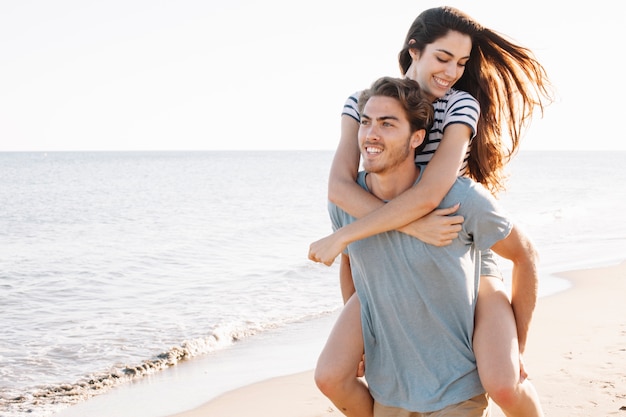 Foto gratuita novio llevando novia joven por la playa