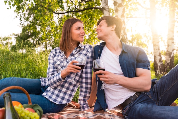 Novio y novia bebiendo vino en picnic