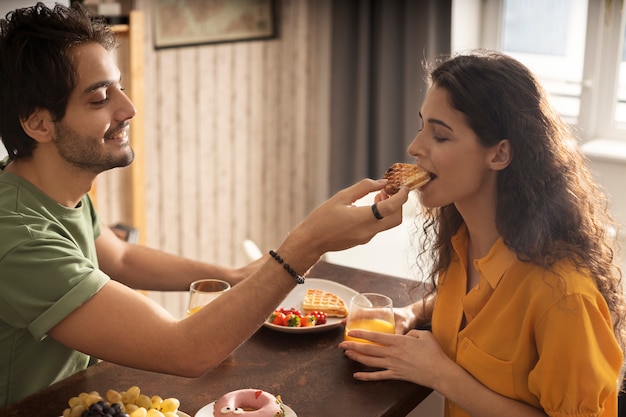 Novio y novia comiendo waffles juntos en casa