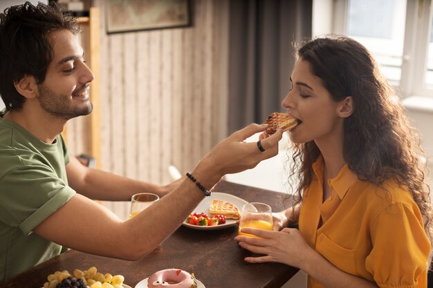 Novio y novia comiendo waffles juntos en casa