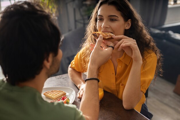 Novio y novia comiendo waffles juntos en casa