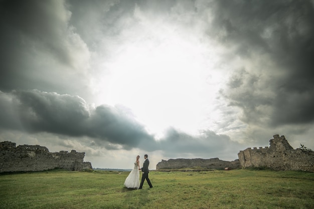 Foto gratuita novio y novia paseando con unas ruinas de fondo