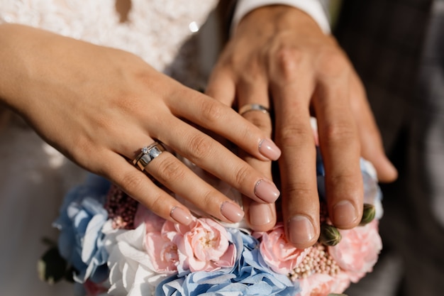 Novio y novia ponen sus manos sobre las flores