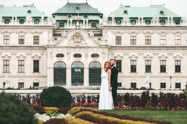 Novio y novia posando con un edificio de fondo