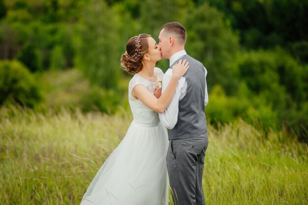 Novio y novia en vestido de boda en la naturaleza. El novio besa a su novia