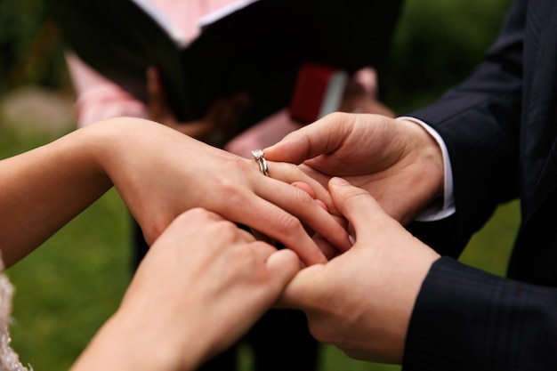 El novio pone el anillo de bodas en el dedo de la novia