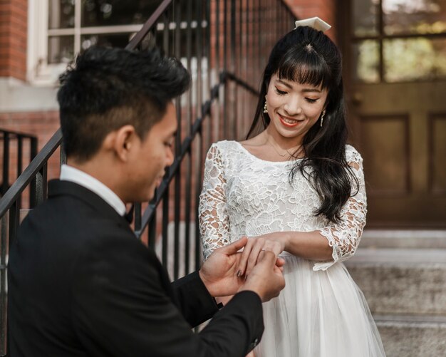 Novio poniendo el anillo de bodas en el dedo de la novia