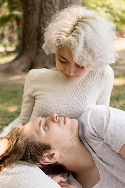 Novio relajándose en el regazo de la novia mientras está al aire libre