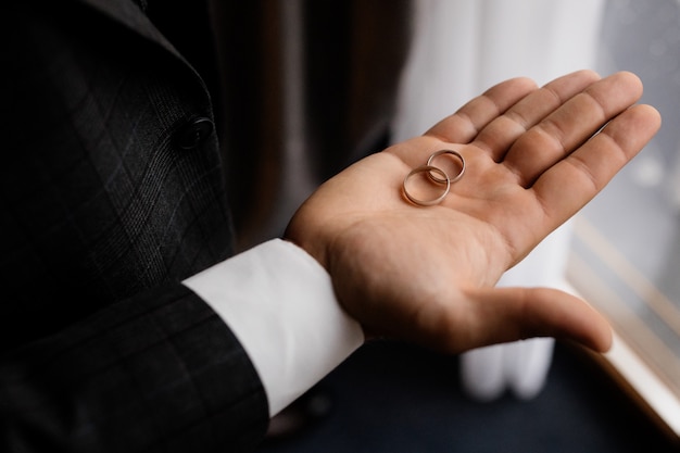 Foto gratuita el novio sostiene en su palma dos anillos de boda