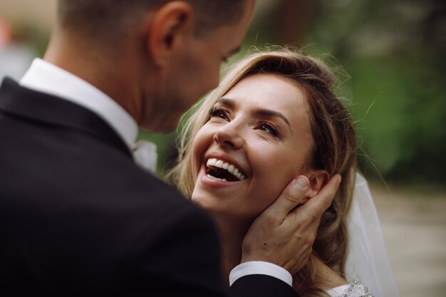 El novio tiene a la novia tierna en sus brazos mientras ella lo mira