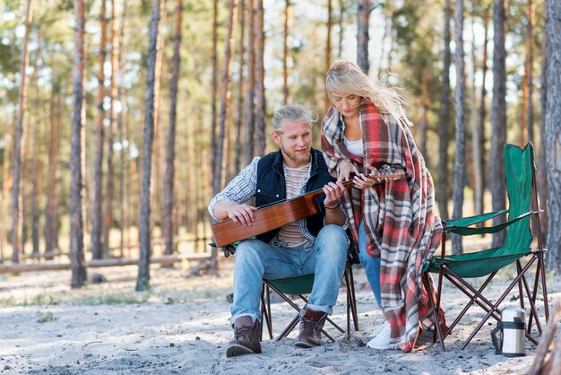 Foto gratuita novio tocando la guitarra acústica en el bosque