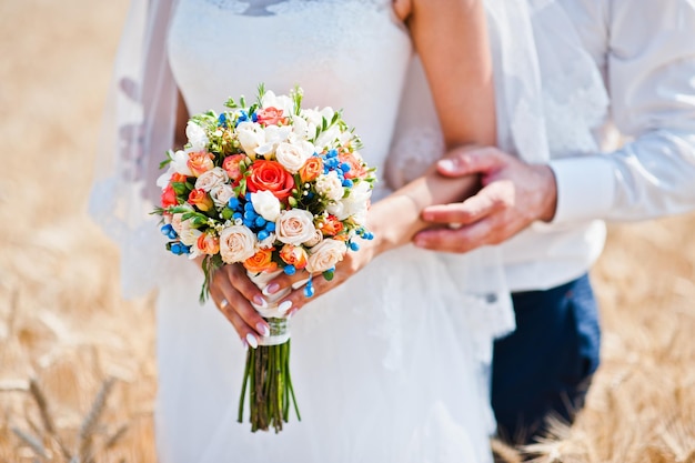 Novios de moda y felices en el campo de trigo en un día soleado