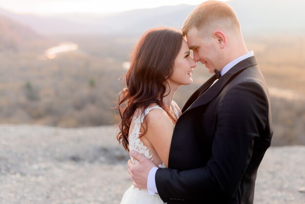 Novios un momento antes de un beso, mirándose en el atardecer al aire libre