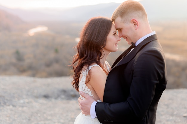 Novios un momento antes de un beso, mirándose en el atardecer al aire libre