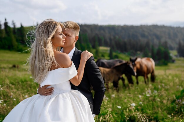 Novios en paisaje de montaña con caballos