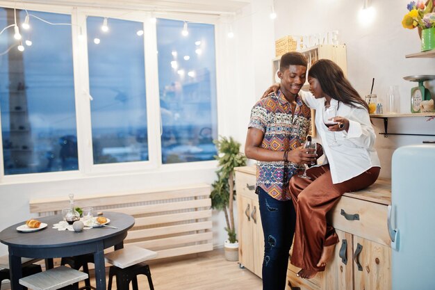 Novios de pareja afroamericana bebiendo vino en la cocina en su cita romántica