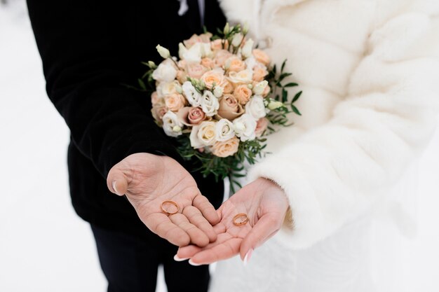 Los novios sostienen los anillos de boda en sus palmas, sin rostro