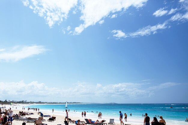 Nubes blancas cuelgan sobre la playa soleada donde la gente descansa