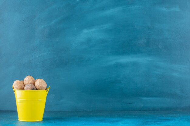 Nueces sin cáscara en un balde sobre la superficie azul