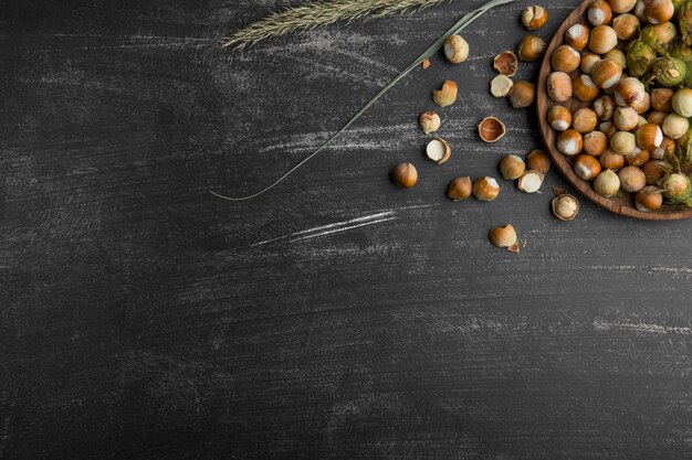 Nueces en cáscaras verdes en una bandeja de madera y sobre la mesa de piedra