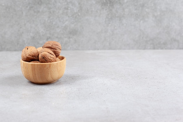 Nueces en un cuenco de madera sobre fondo de mármol. Foto de alta calidad