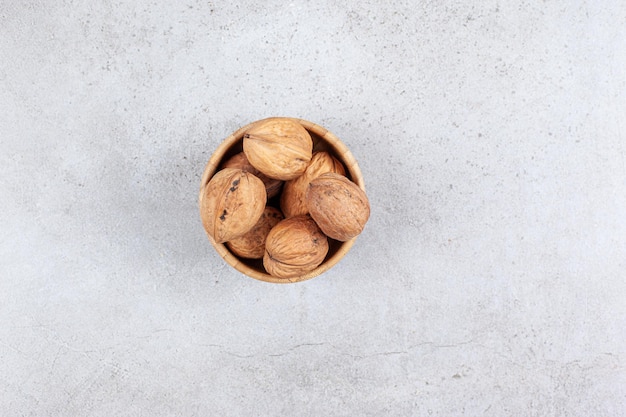 Nueces en un cuenco de madera sobre fondo de mármol.