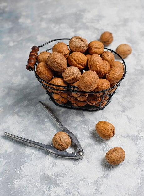 Foto gratuita nueces enteras con cáscara en una canasta de metal para alimentos, nueces. vista superior sobre hormigón