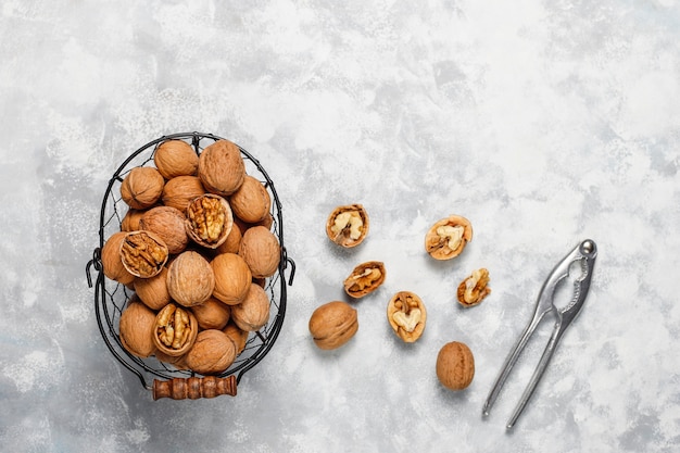 Nueces enteras con cáscara en una canasta de metal para alimentos, nueces. Vista superior sobre hormigón