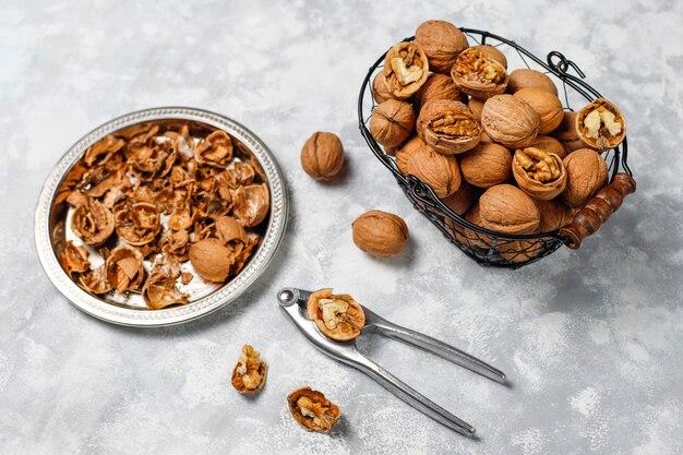 Nueces enteras con cáscara en una canasta de metal para alimentos, nueces. Vista superior sobre hormigón