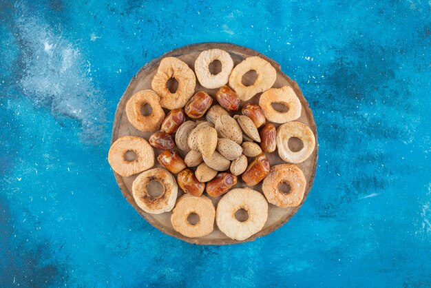 Nueces y frutos secos en un tablero, sobre la mesa azul.