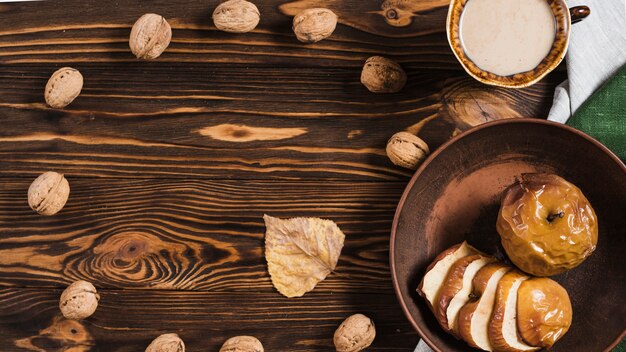 Nueces y hojas de otoño cerca de bebidas y aperitivos