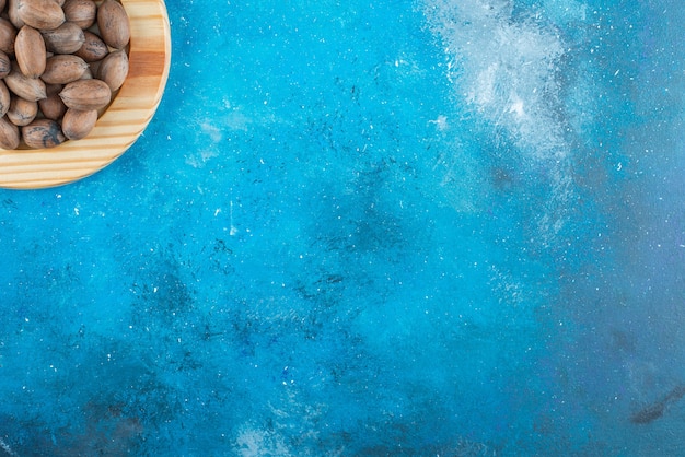 Nueces de pacana en una placa de madera sobre la superficie azul