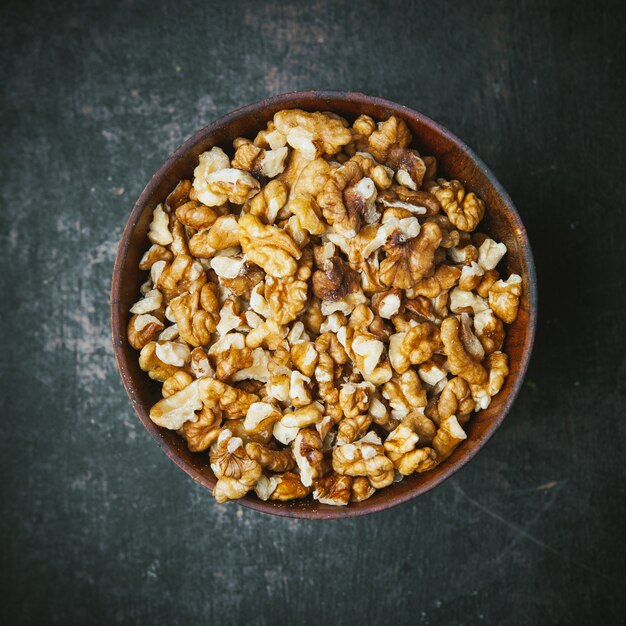 Nueces peladas en un recipiente marrón sobre la mesa oscura