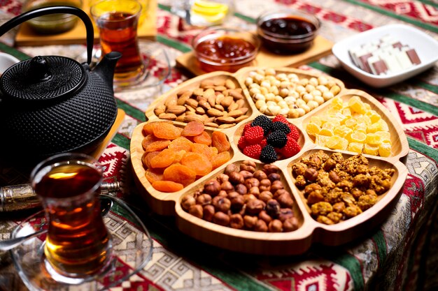 Nueces que sirven en un plato de bambú en forma de flor con almendras, avellanas, nueces, albaricoques secos y dulces