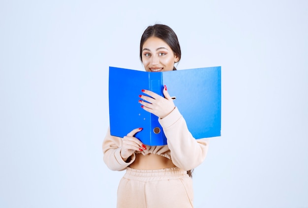 Nueva asistente escondiendo su rostro detrás de una carpeta azul