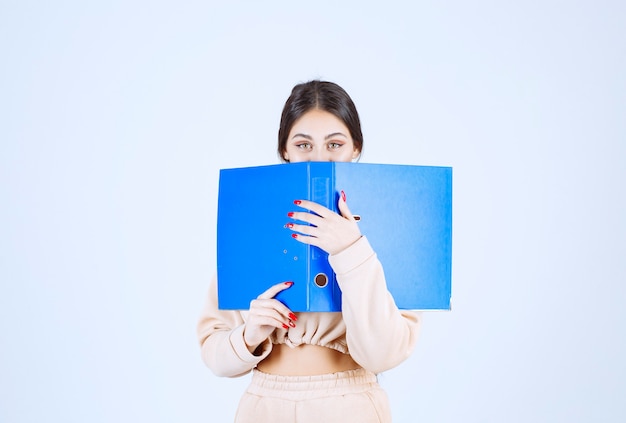 Nueva asistente escondiendo su rostro detrás de una carpeta azul