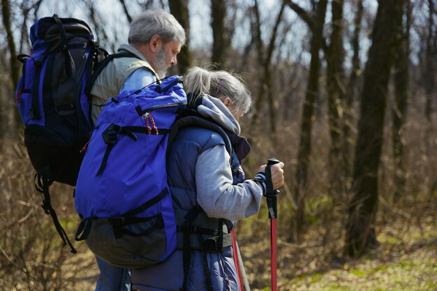 Nueva experiencia genial. Pareja de familia de hombre y mujer en traje de turista caminando en el césped cerca de árboles en un día soleado. Concepto de turismo, estilo de vida saludable, relajación y convivencia.