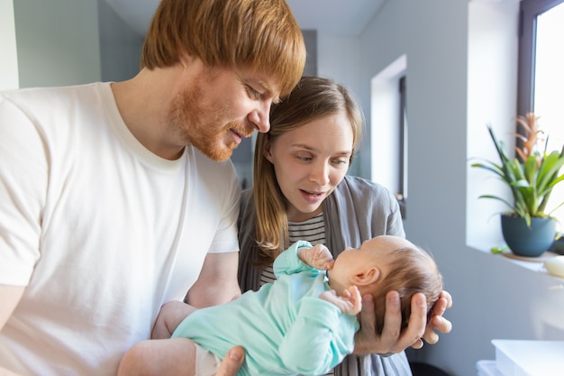 Nueva madre y padre sosteniendo y abrazando al bebé