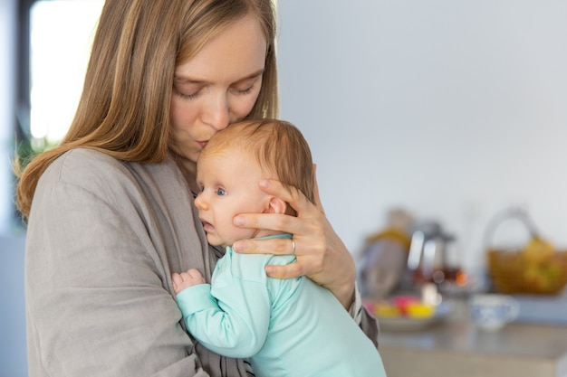 Nueva mamá abrazando y besando bebé