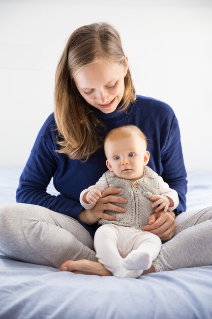 Nueva mamá joven positiva que detiene a su pequeño bebé dulce