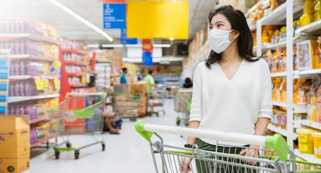 Nueva normalidad después de la epidemia de covid, joven mujer asiática inteligente que compra un nuevo estilo de vida en el supermercado con protector facial o protección con máscara, elija vegetales frescos de frutas, nuevo estilo de vida normal