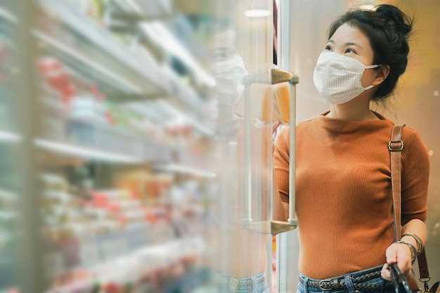 Nueva normalidad después de la epidemia de covid, joven mujer asiática inteligente que compra un nuevo estilo de vida en el supermercado con protector facial o protección con máscara, elija vegetales frescos de frutas, nuevo estilo de vida normal