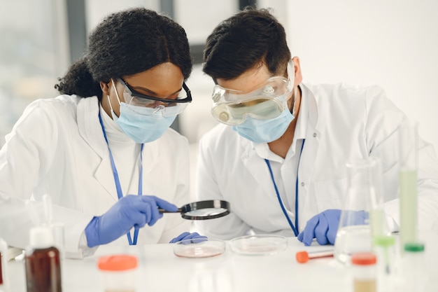 Nueva prueba. Investigadores calificados concentrados vistiendo uniforme. Haciendo prueba, creando vacuna.